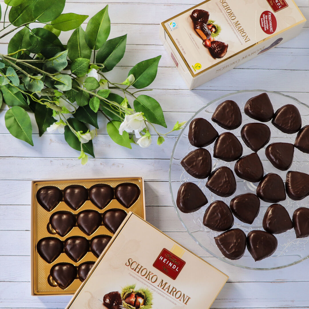 Teller mit Schoko Maroni und offener Pralinenschachtel sowie Grünzeug-Dekoration