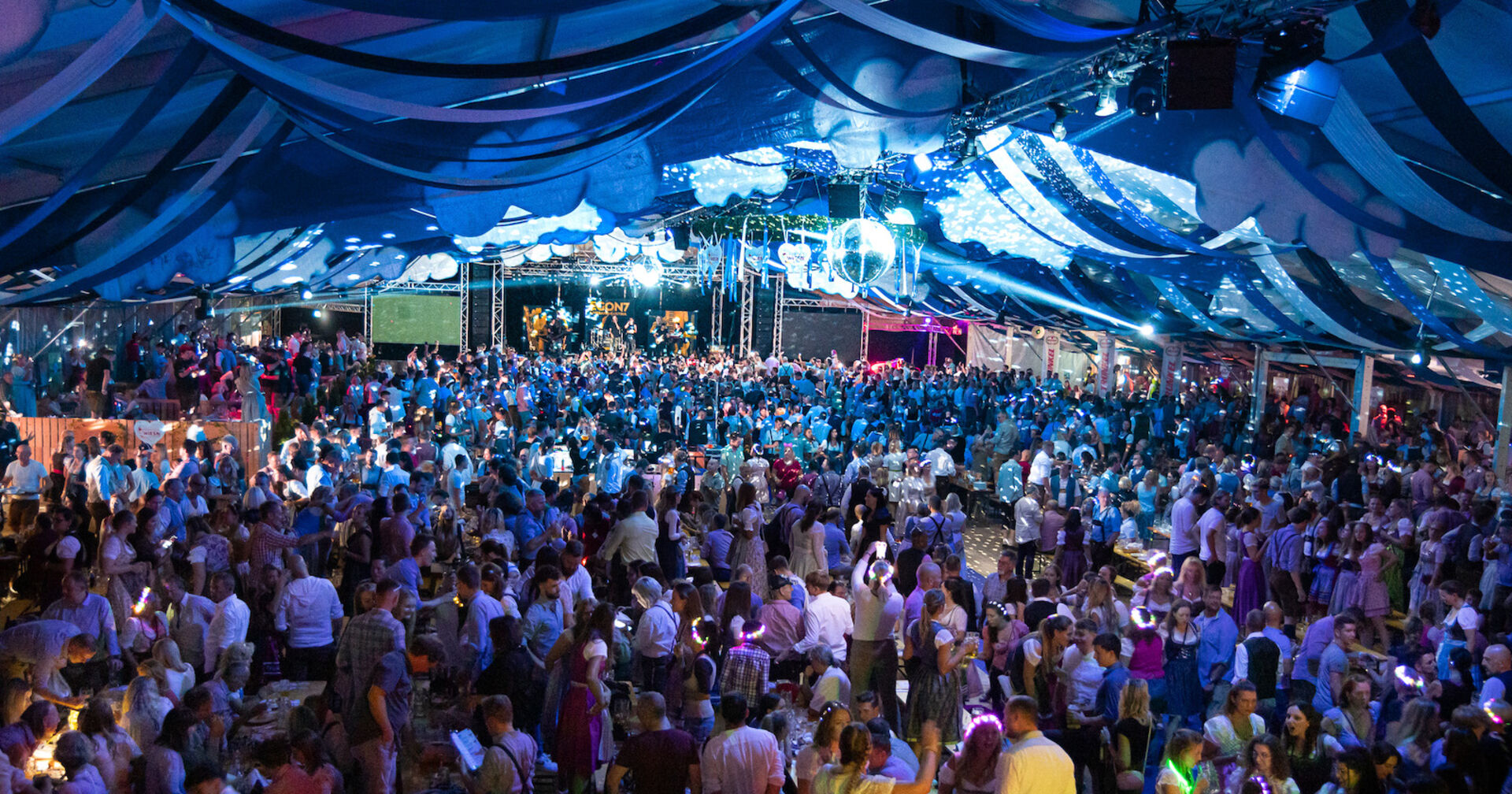 Festzelt innen voller Menschen, in blaues Licht getaucht
