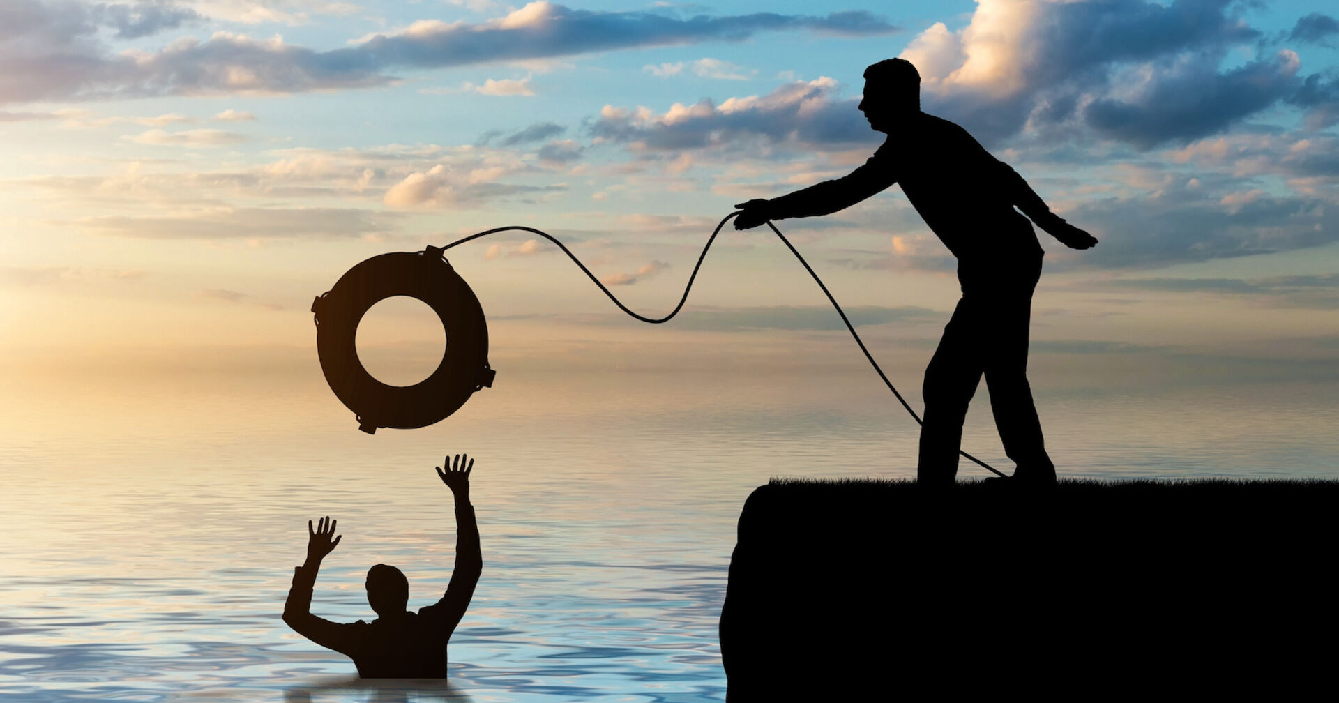 Shilouetten von ertrinkendem und Retter auf dem Kai, der Rettungsring wirft