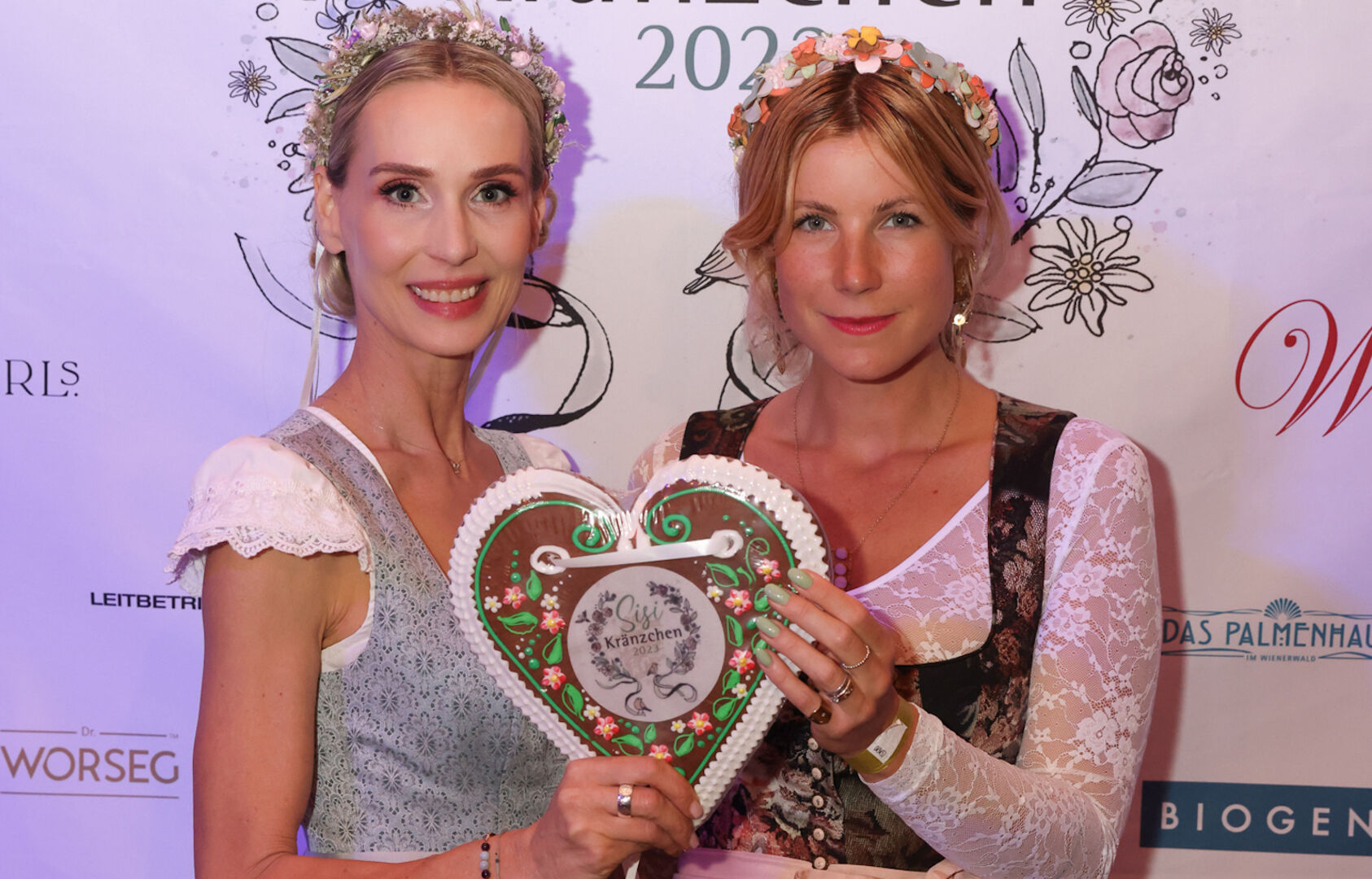 Zwei blonde Frauen halten in ihrer Mitte ein Lebkuchenherz hoch