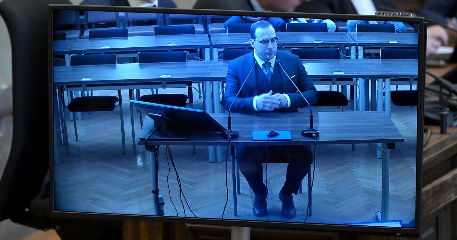 Aufnahme eines Monitors, auf dem Florian Teichtmeister während seiner Gerichstverhandlung zu sehen ist.