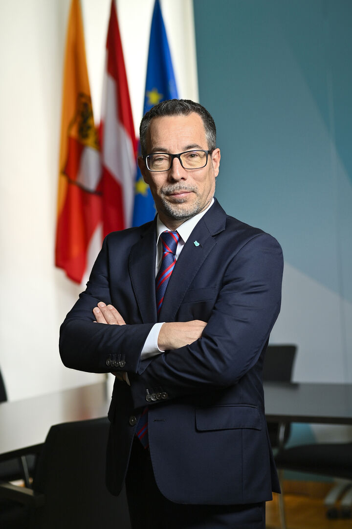 Markus Malle, der vor den Fahnen Kärntens, Österreichs sowie der EU steht