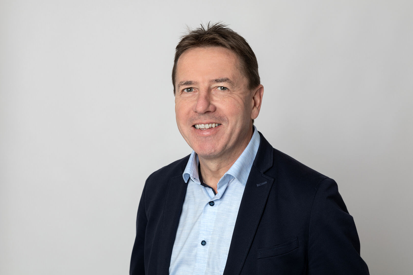 Porträtfoto von Erwin Angerer, der ein schwarzes Sakko samt hellblauem Hemd trägt