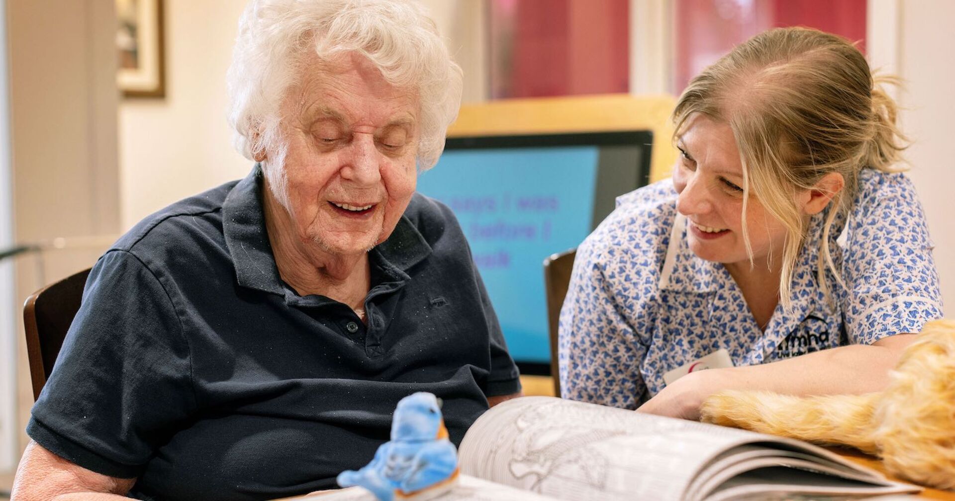 Eine alte und eine junge Frau lesen gemeinsam ein Buch.