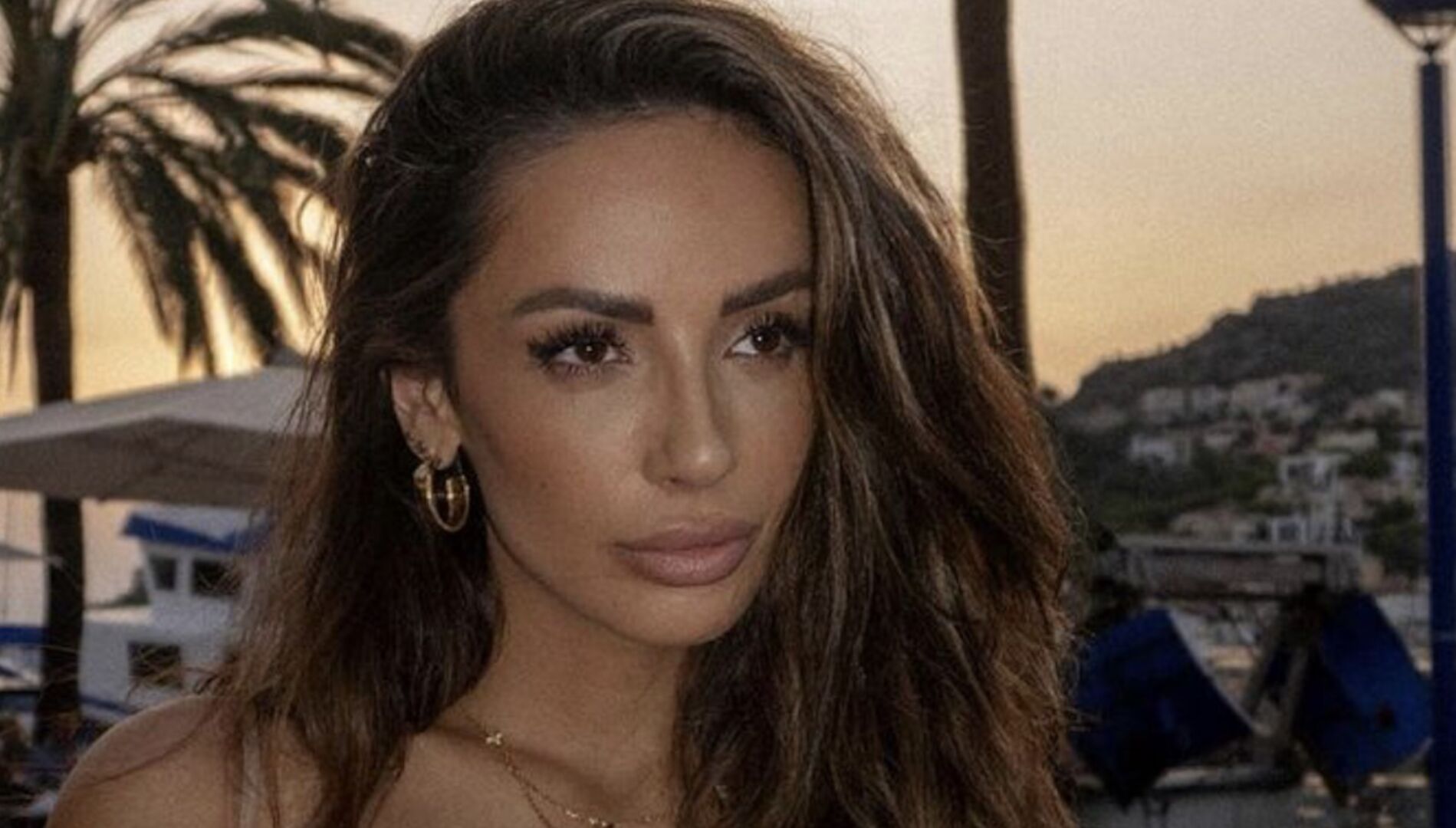 Bachelorette Jennifer Saro mit offenen braunen Haaren vor einer Palme