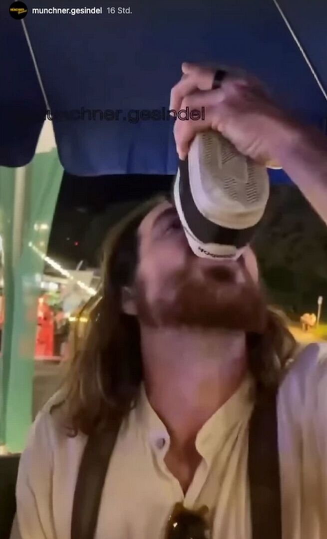 Langhaariger Mann trinkt Bier aus seinem Turnschuh.