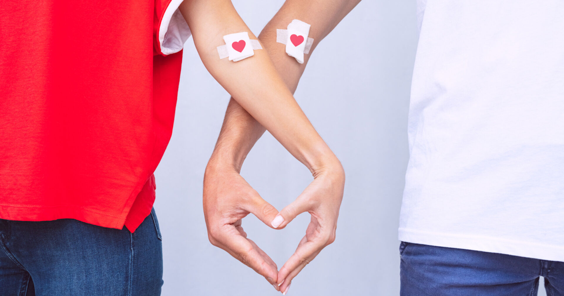 Zwei Blutspender mit Herzpflaster formen mit ihren Fingern ein Herz| Credit: istock.com/Daria Kulkova
