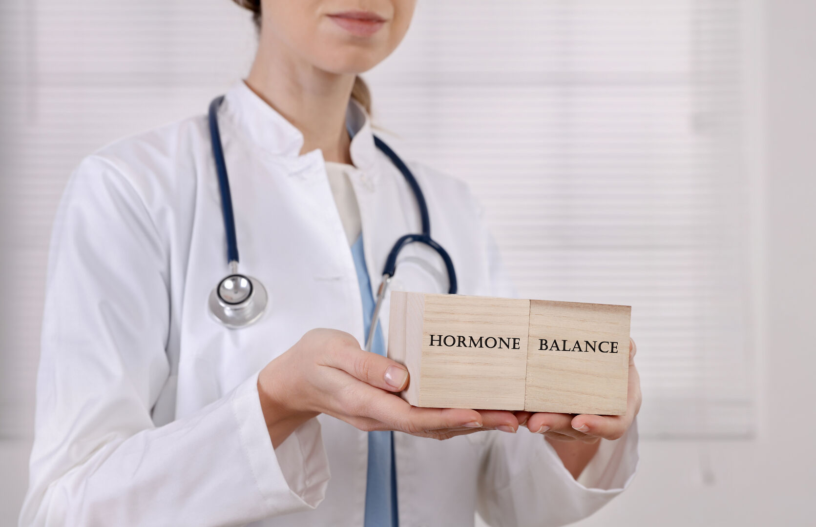 Ärztin hält Holzwürfel mit Aufschrift &quot;HORMONE BALANCE&quot; in den Händen