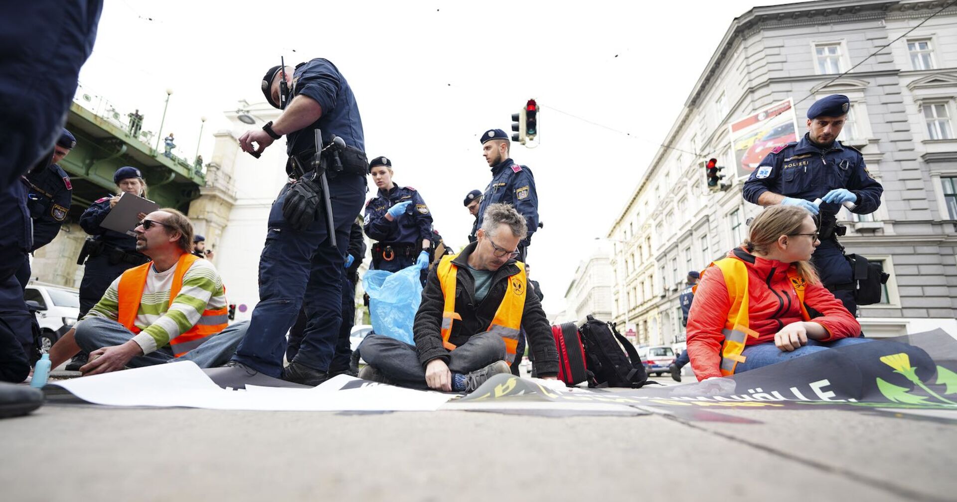 Klimakleber kleben auf der Straße. Polizisten sind vor Ort.