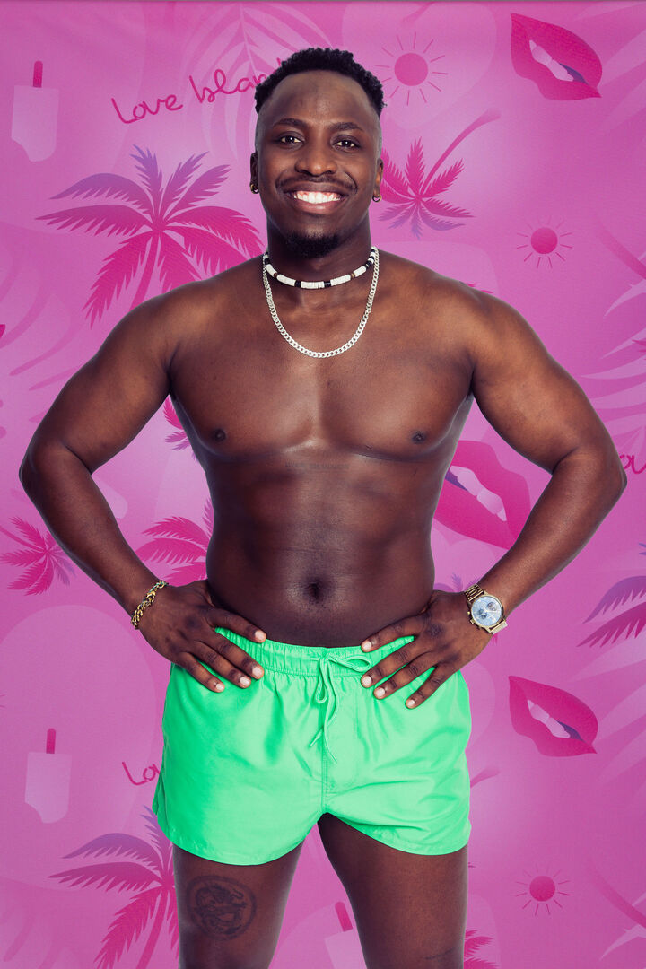 Dunkelhäutiger Mann vor pinker Love Island Wand