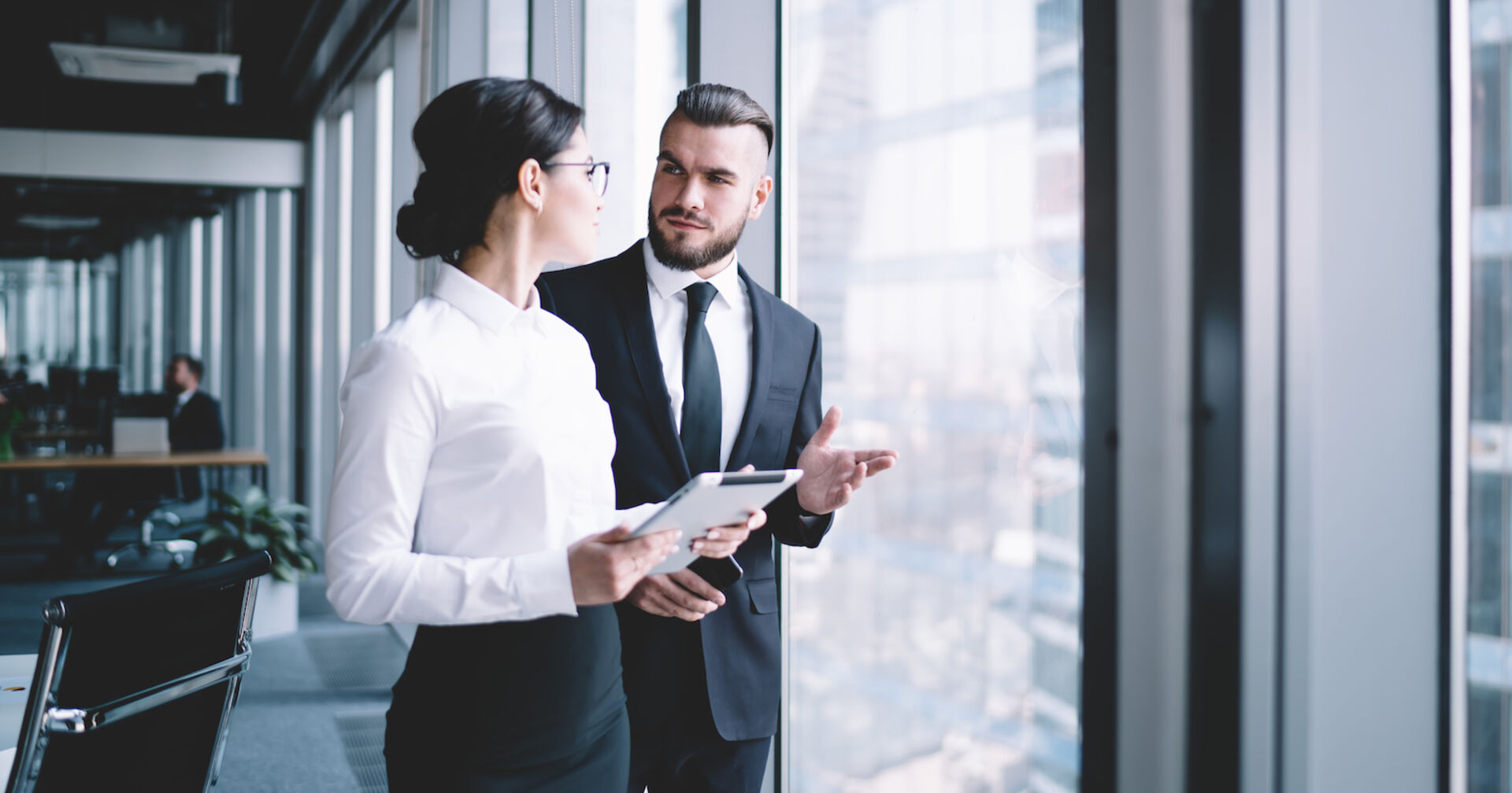 Junger Mann im dunklen Anzug spricht mit junger Frau in weißer Bluse und dunklem Rock| Credit: istock.com/GaudiLab