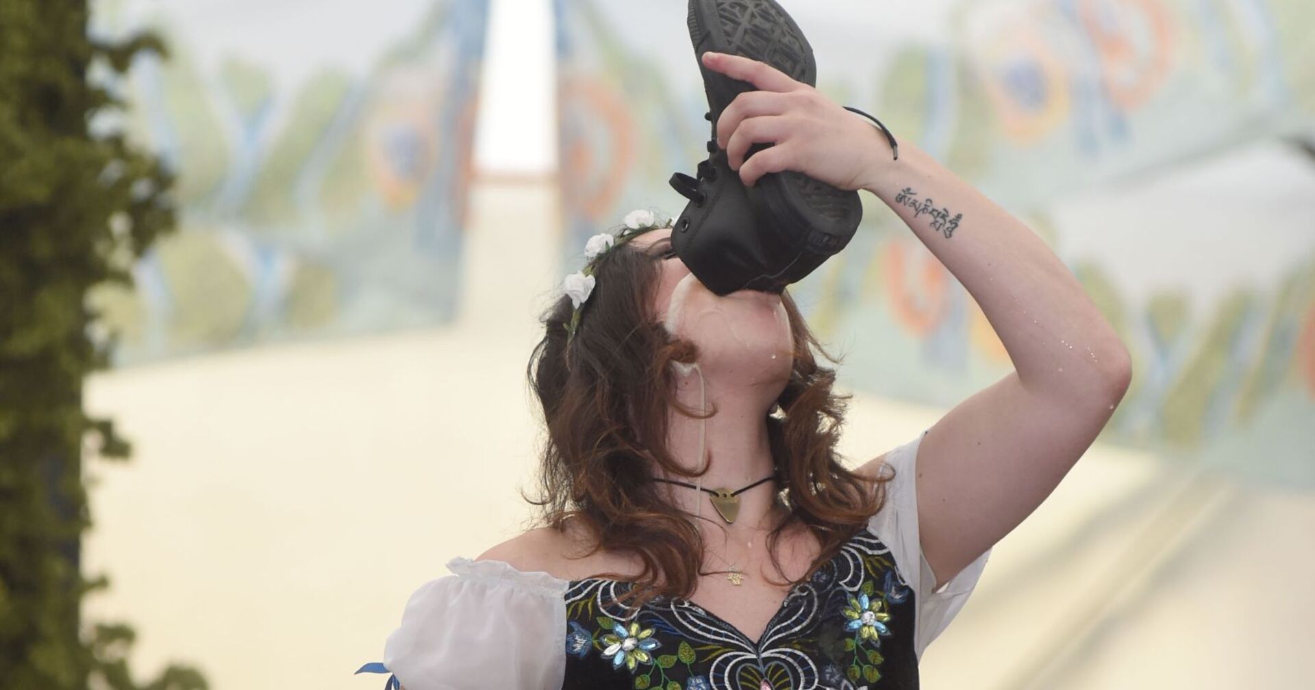 Eine Frau trinkt ihr Bier aus dem eigenen Schuh.