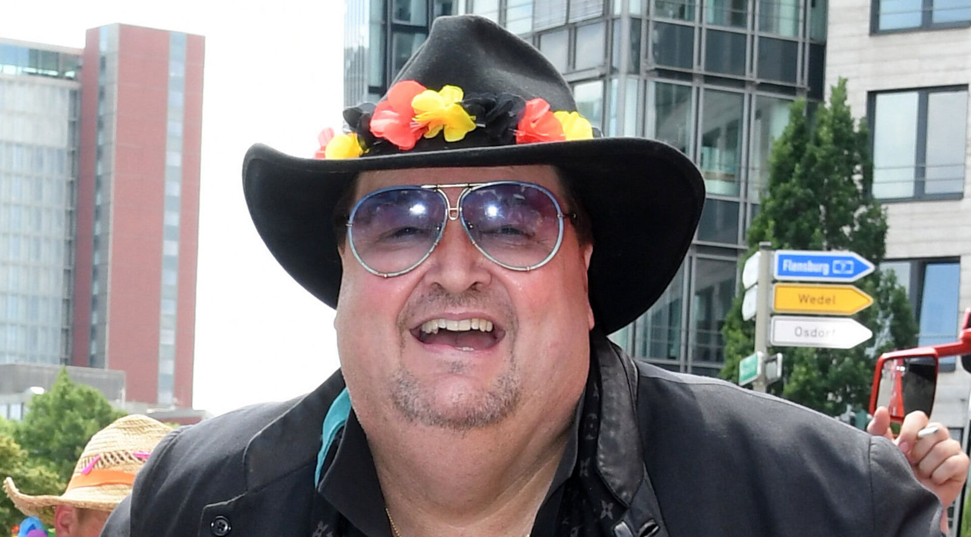 Andreas Ellermann mit einem schwarzen Hut und Blumendekoration in den Farben der Deutschland Flagge.