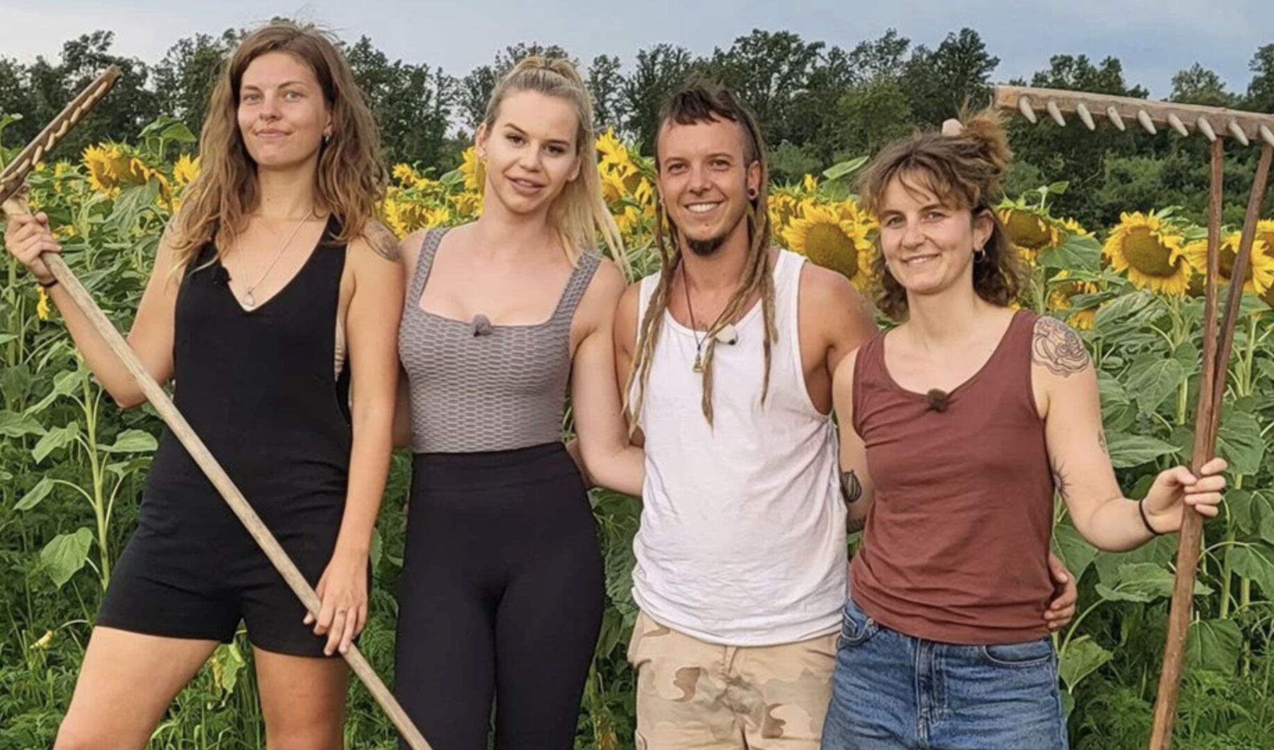 Bauer sucht Frau Kandidat Philip mit Dreadlocks und seinen Kandidatinnen mit Heugabeln vor einem Sonnenblumenfeld.