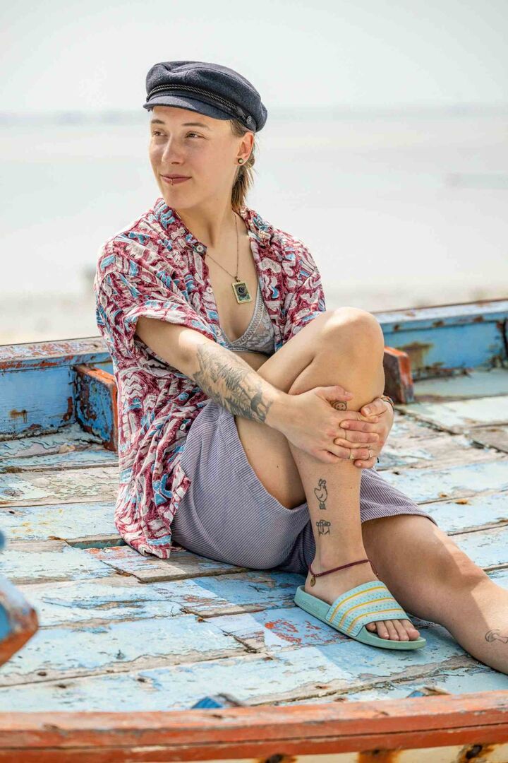 Lucy sitzt auf einem alten Boot am Strand.