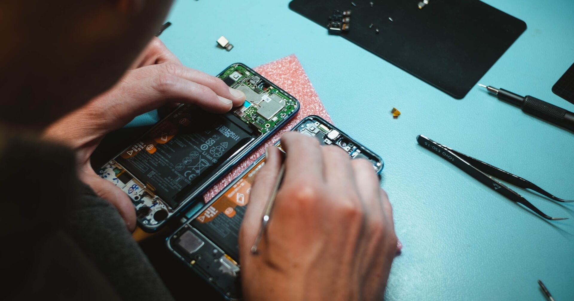 Ein Mann repariert ein aufgeschraubtes Smartphone