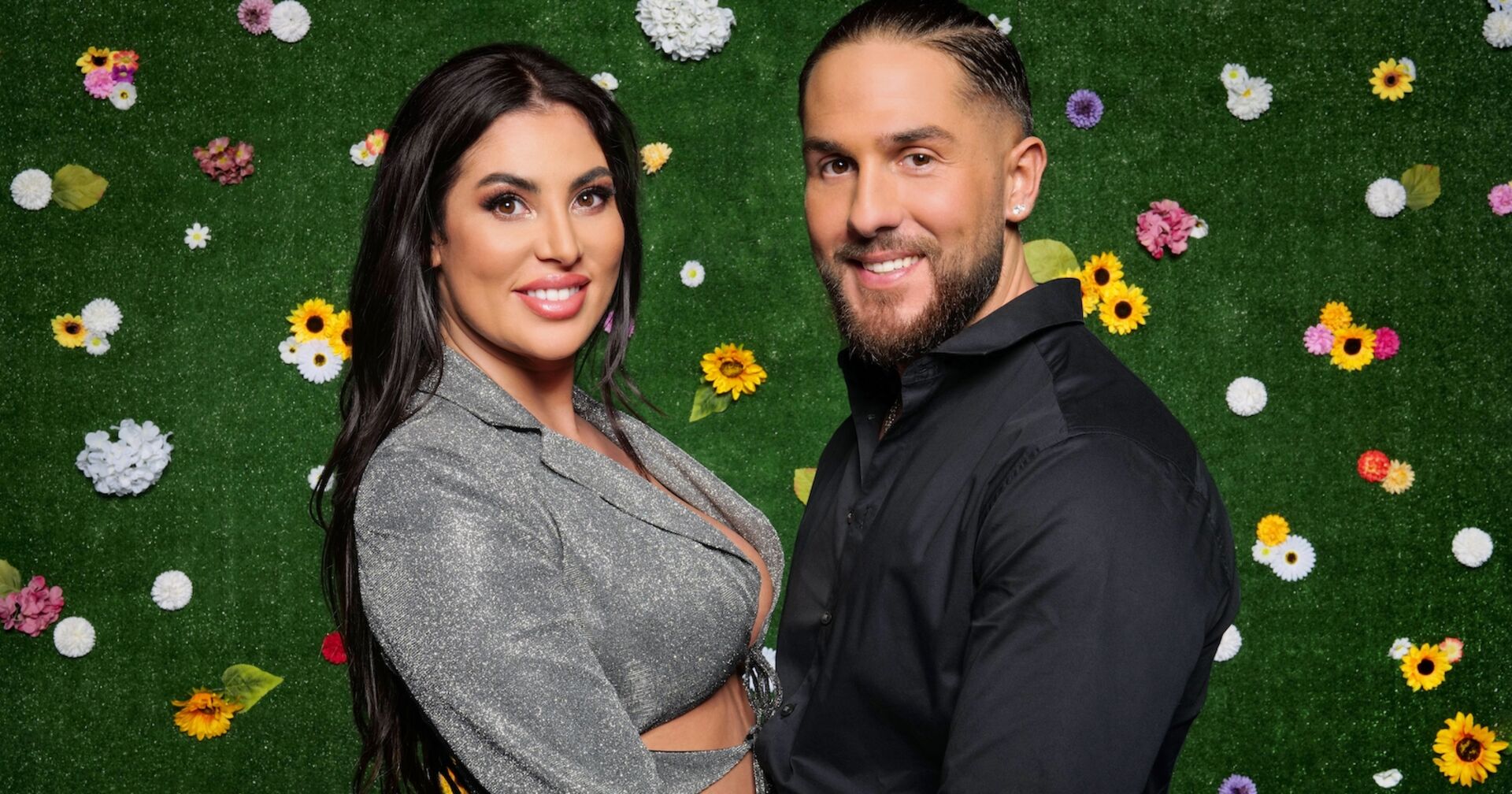 Ricarda und Maurice vom Sommerhaus der Stars vor einer Wand mit Blumen.