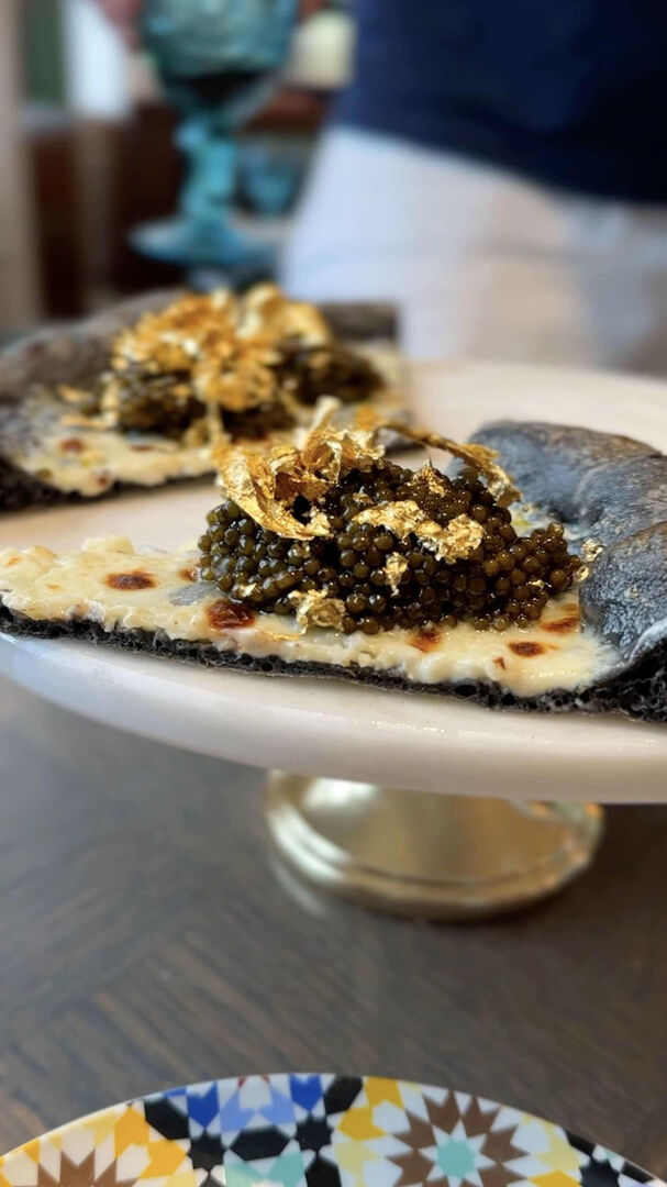 Eine violette Pizza mit Kaviar und Blattgold auf einem weißen Teller