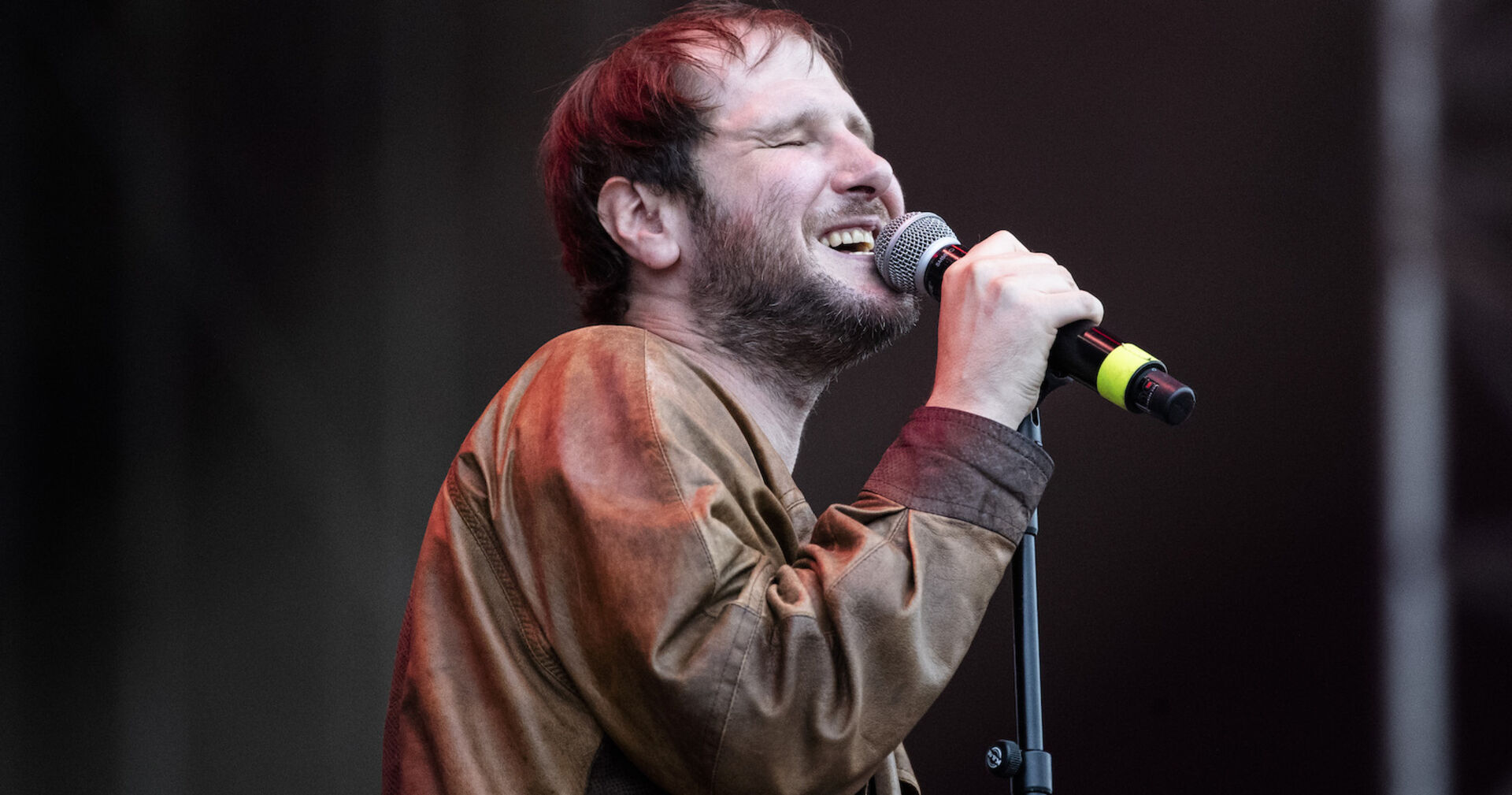 Marco Wanda singt bei einem Konzert in einer braunen Lederjacke