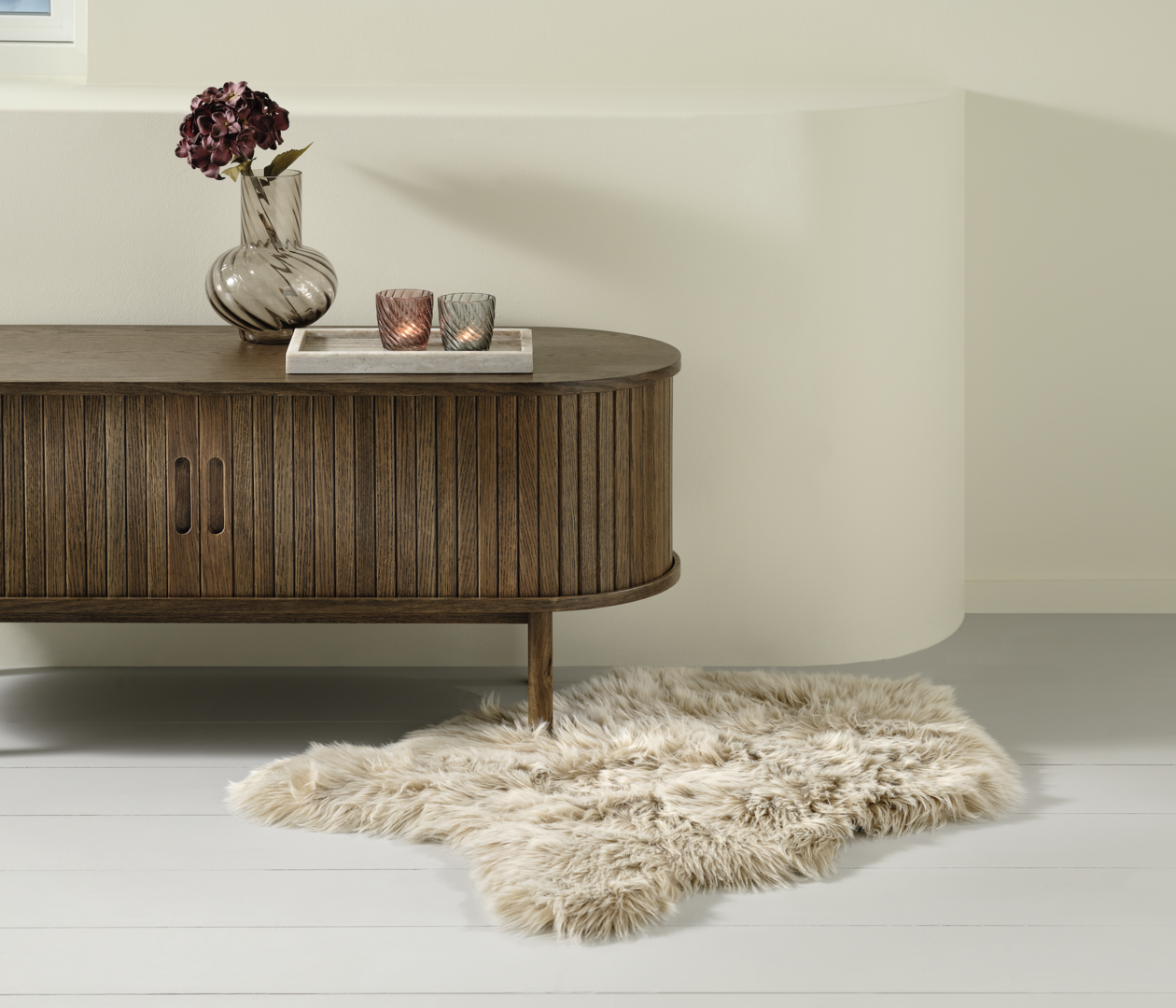 Beiger Fellteppich vor Sideboard