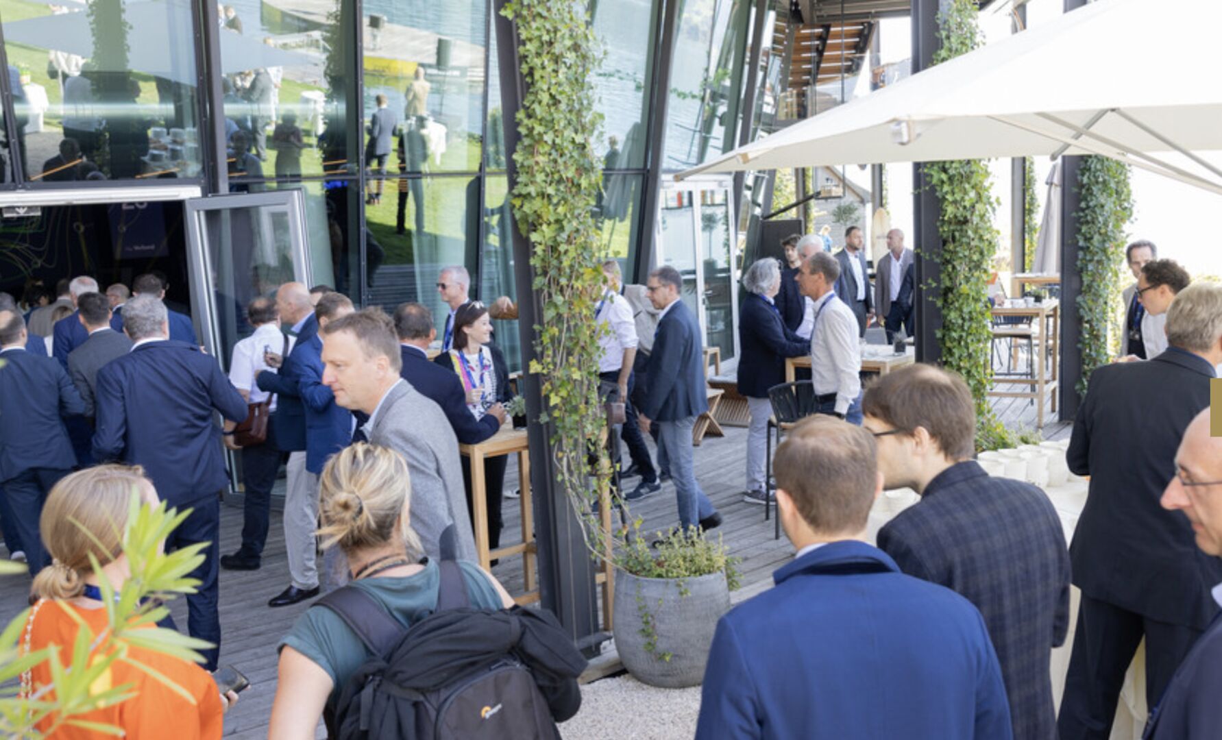 Vor dem Eingang stehen mehrere Menschengruppen und unterhalten sich