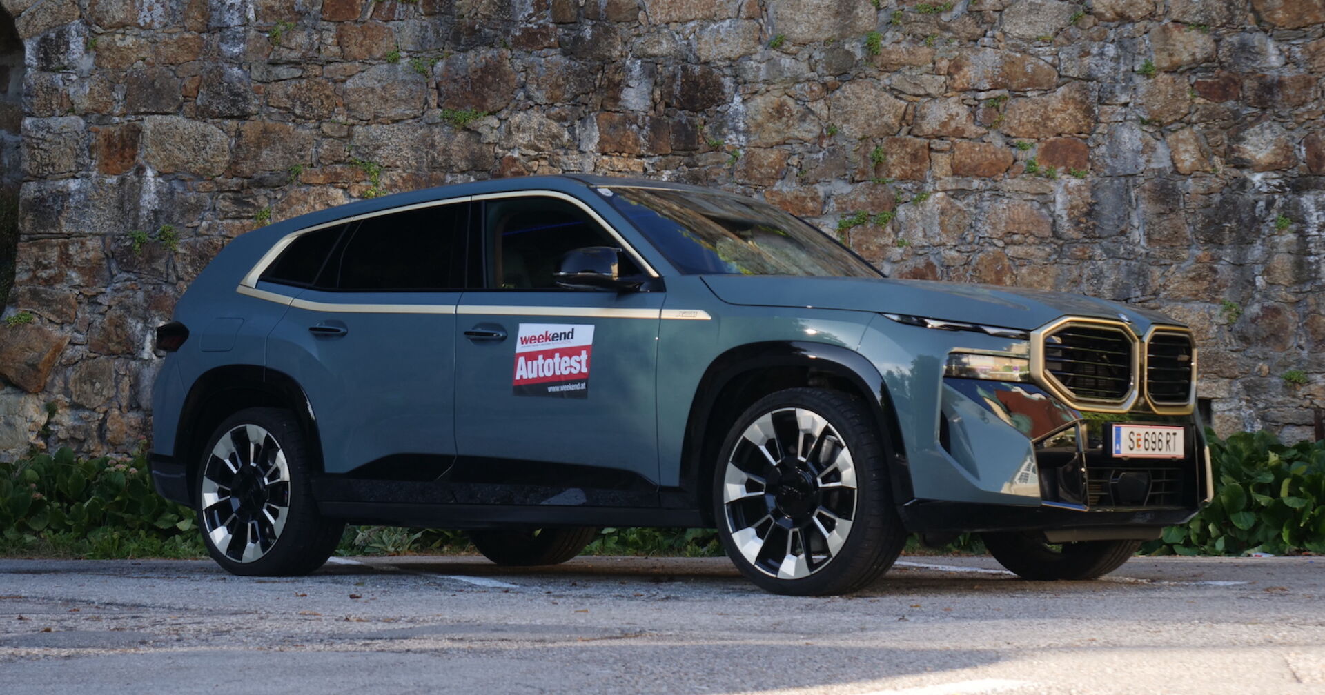 Die Beifahrerseite des BMW XM vor einer Steinmauer