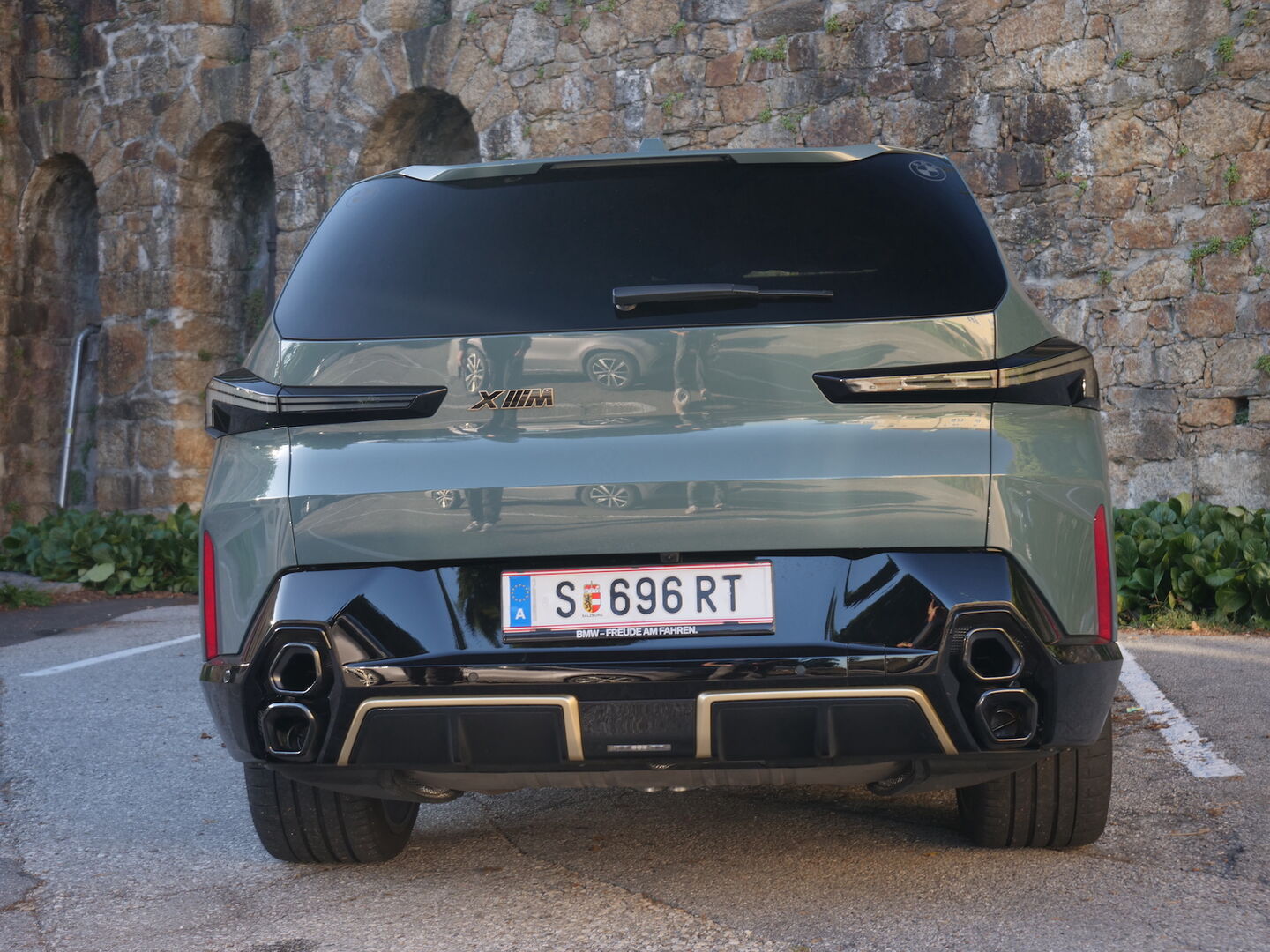 Das Heck des BMW XM vor einer Steinmauer