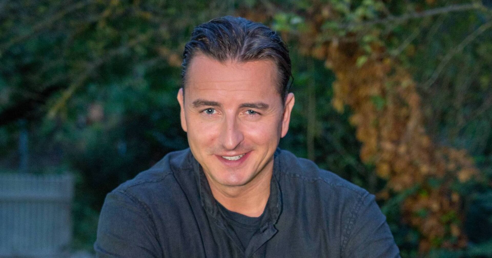 Andreas Gabalier mit zurück gegelten kurzen Haaren und einem grauen Pullover.