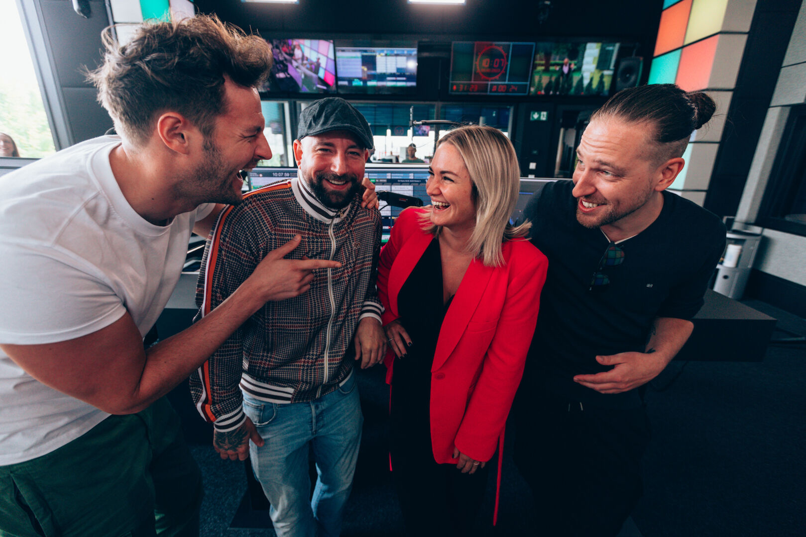 Paul Pizzera, Christopher Seiler, Gabi Hiller und Daniel Fellner im Ö3 Studio. Gabi Hiller lacht und trägt einen knallroten Blazer.