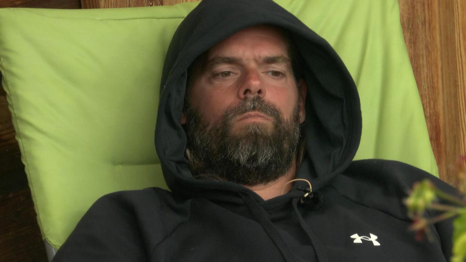 Forsthaus Rampensau Teilnehmer Daniel trägt einen schwarzen Hoodie und liegt auf einer grünen Liege.