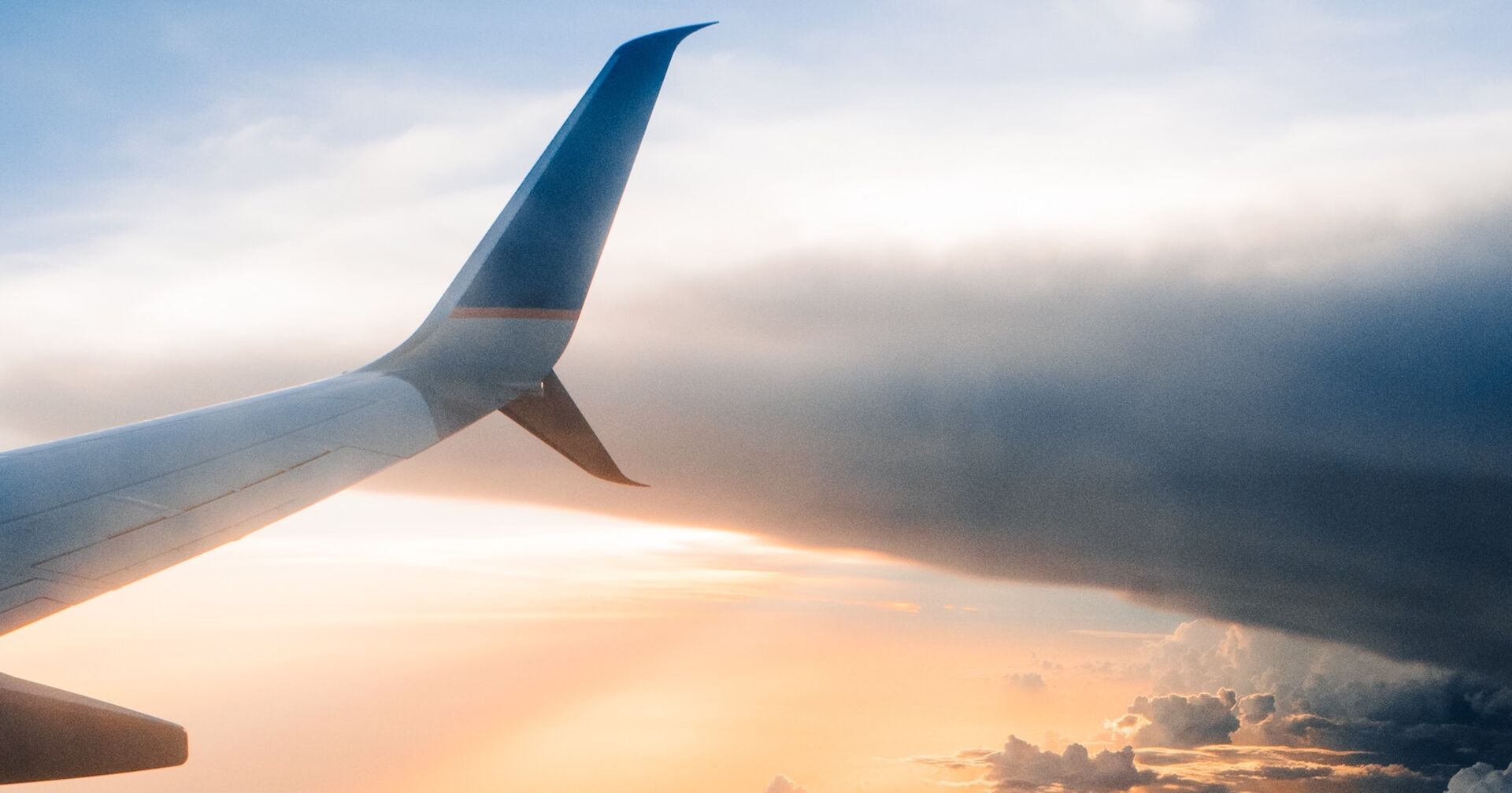 Der Flügel eines Flugzeuges bei Sonnenuntergang im Himmel.