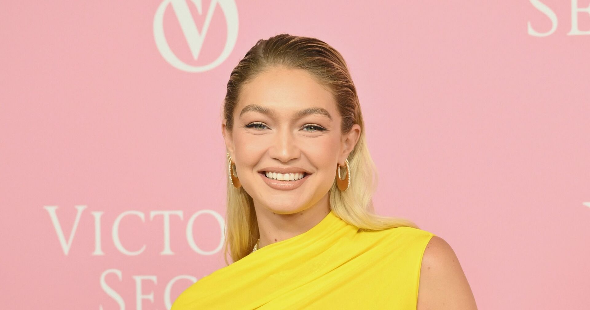 Gigi Hadid im gelbem Kleid vor rosa Victorias Secret Leinwand