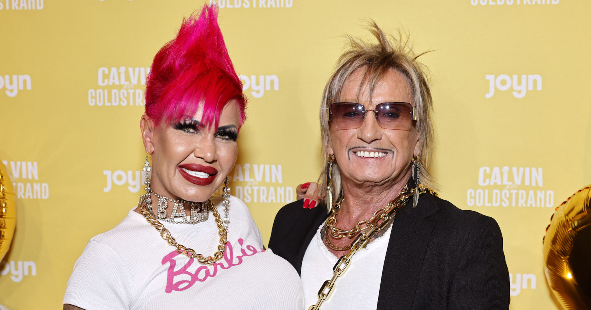 Gina trägt einen pinken Irokesen und ein weißes T-Shirt mit einer Aufschrift &quot;Barbie&quot;. Bert Wollersheim hat blonde Haare und eine verdunkelte Sonnenbrille.