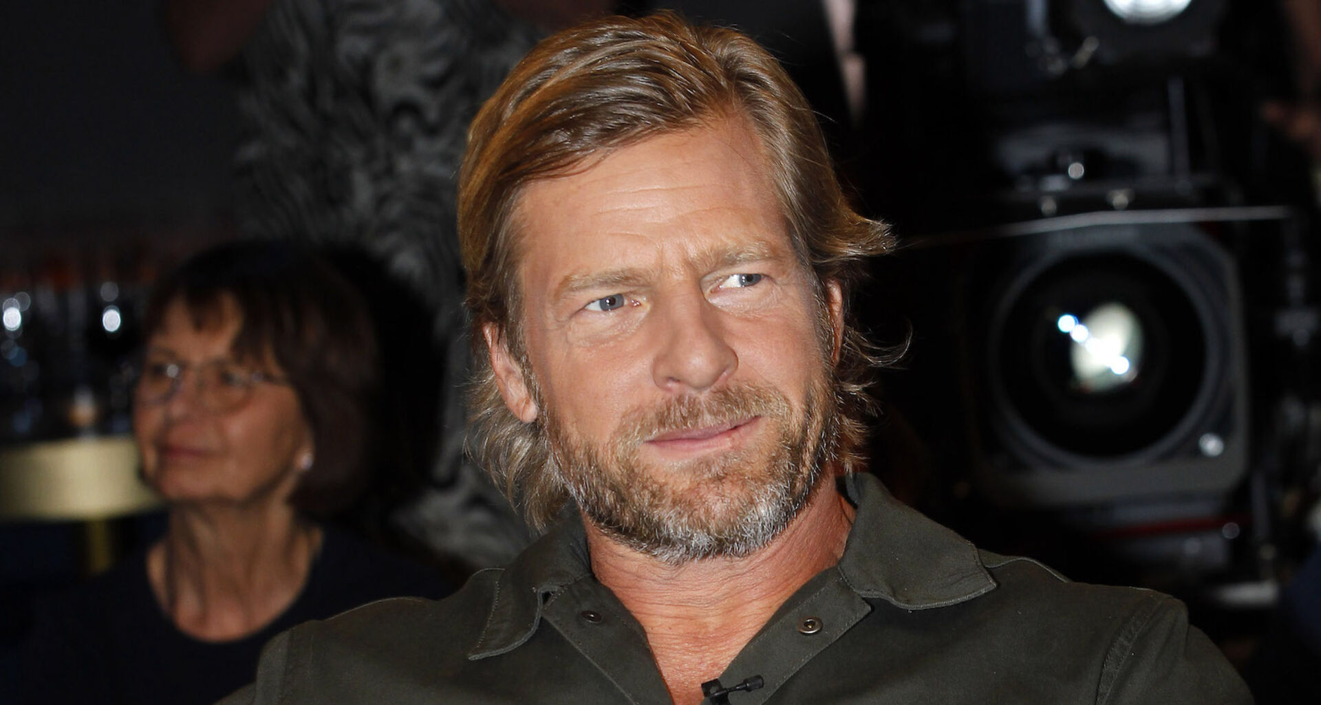 Schauspieler Henning Baum mit einem schwarzen Hemd und leicht gegolten blonden Haaren. Er trägt einen Dreitagebart.