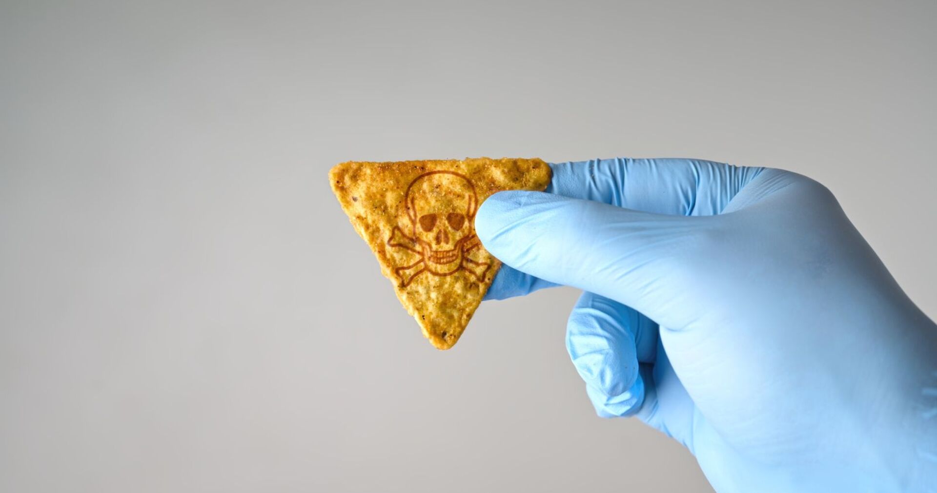 Jemand greift einen Tortilla-Chip mit Einweghandschuhen an.