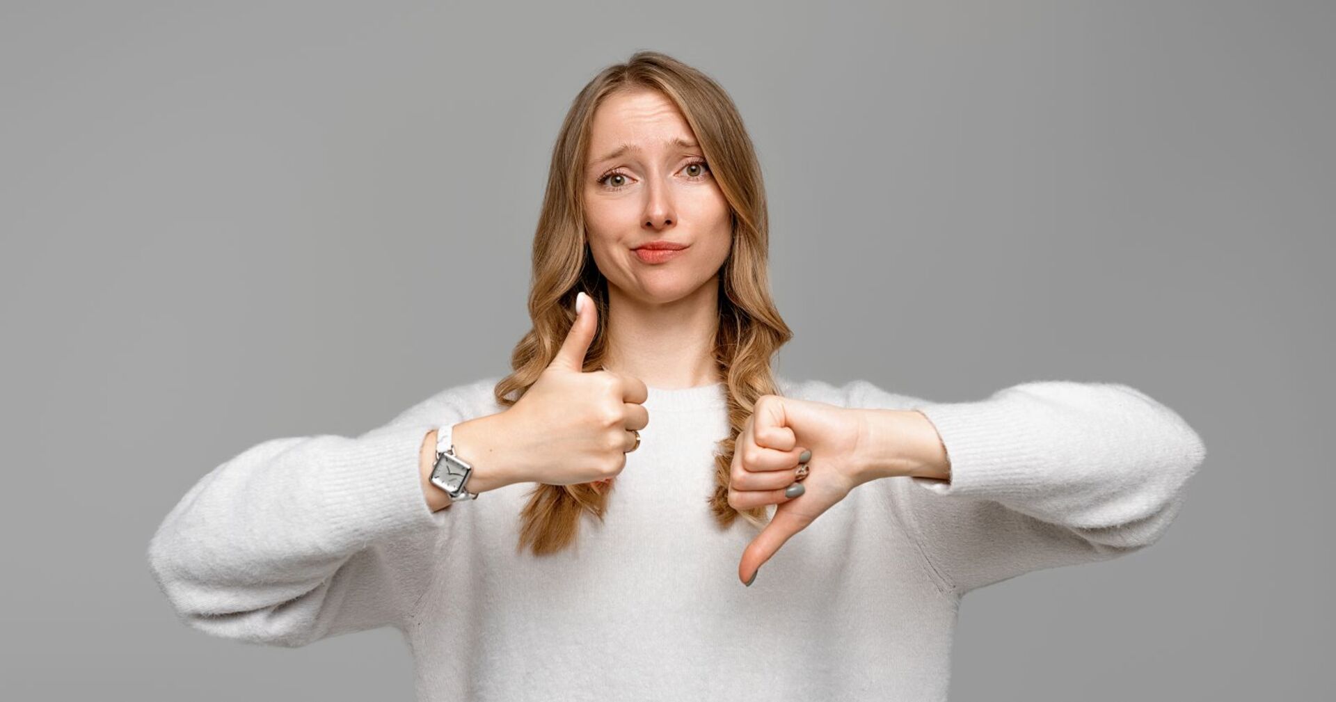 Frau zeigt mit einen Daumen nach oben und mit einem nach unten.