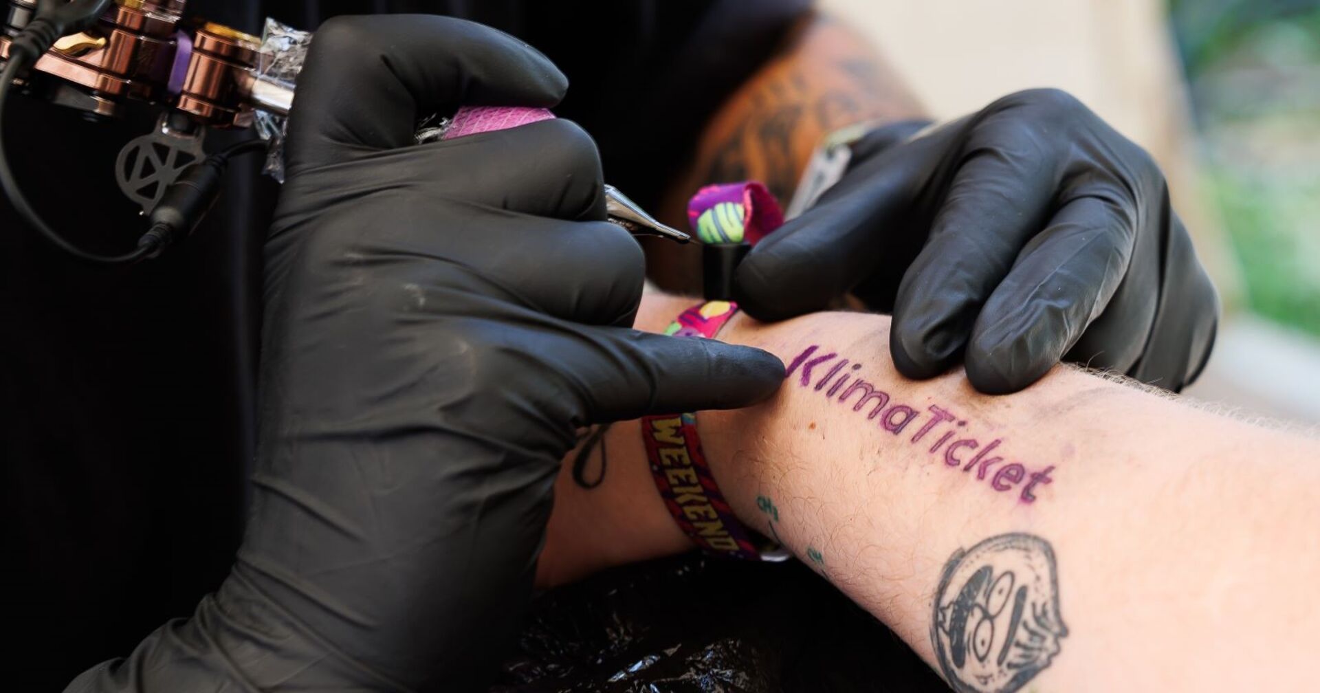 Ein Tättowierer tättowiert den Schriftzug Klimaticket.