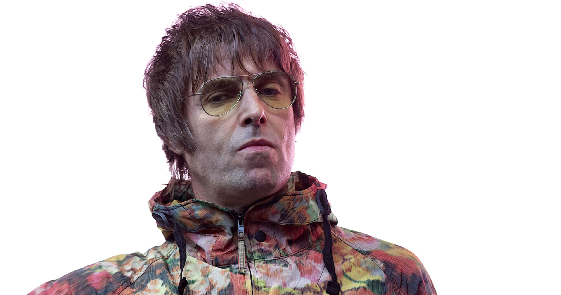 Liam Gallegher von Oasis mit einer gelben Sonnenbrille und einer bunten Jacke.