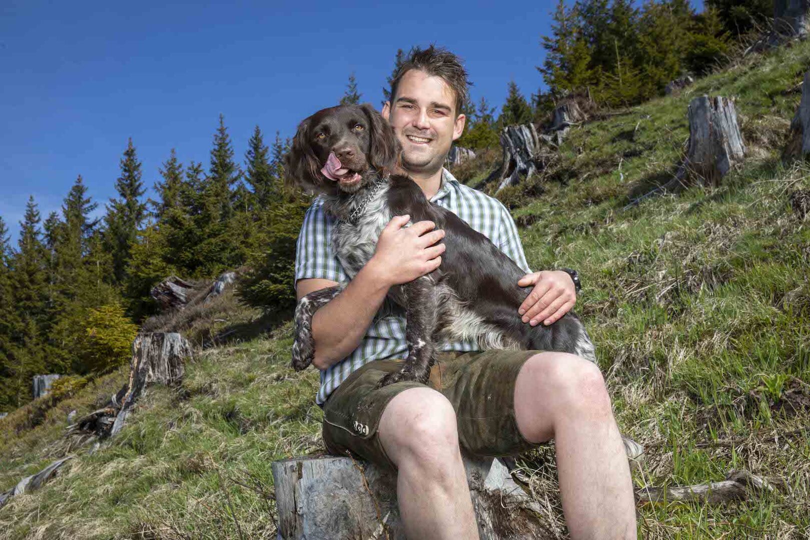 Mathias von Bauer sucht Frau mit einem Hund auf dem Schoss auf einer grünen Alm.