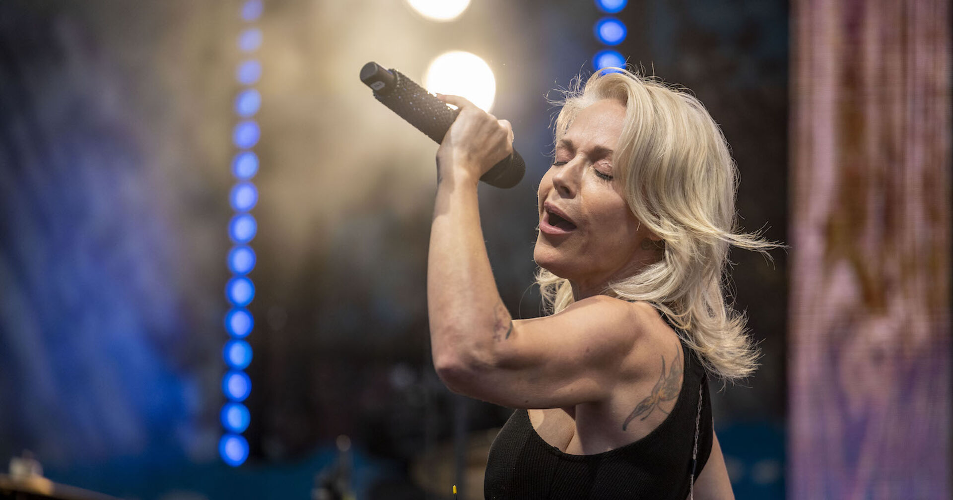 Schlagerstar Michelle mit offenen blonden Haaren, einem Mikrofon singend auf der Bühne.