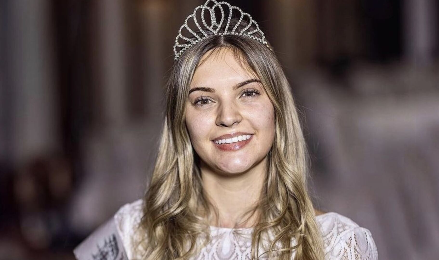 Eine ungeschminkte Frau mit Krone auf dem Kopf und blonden langen Haaren.