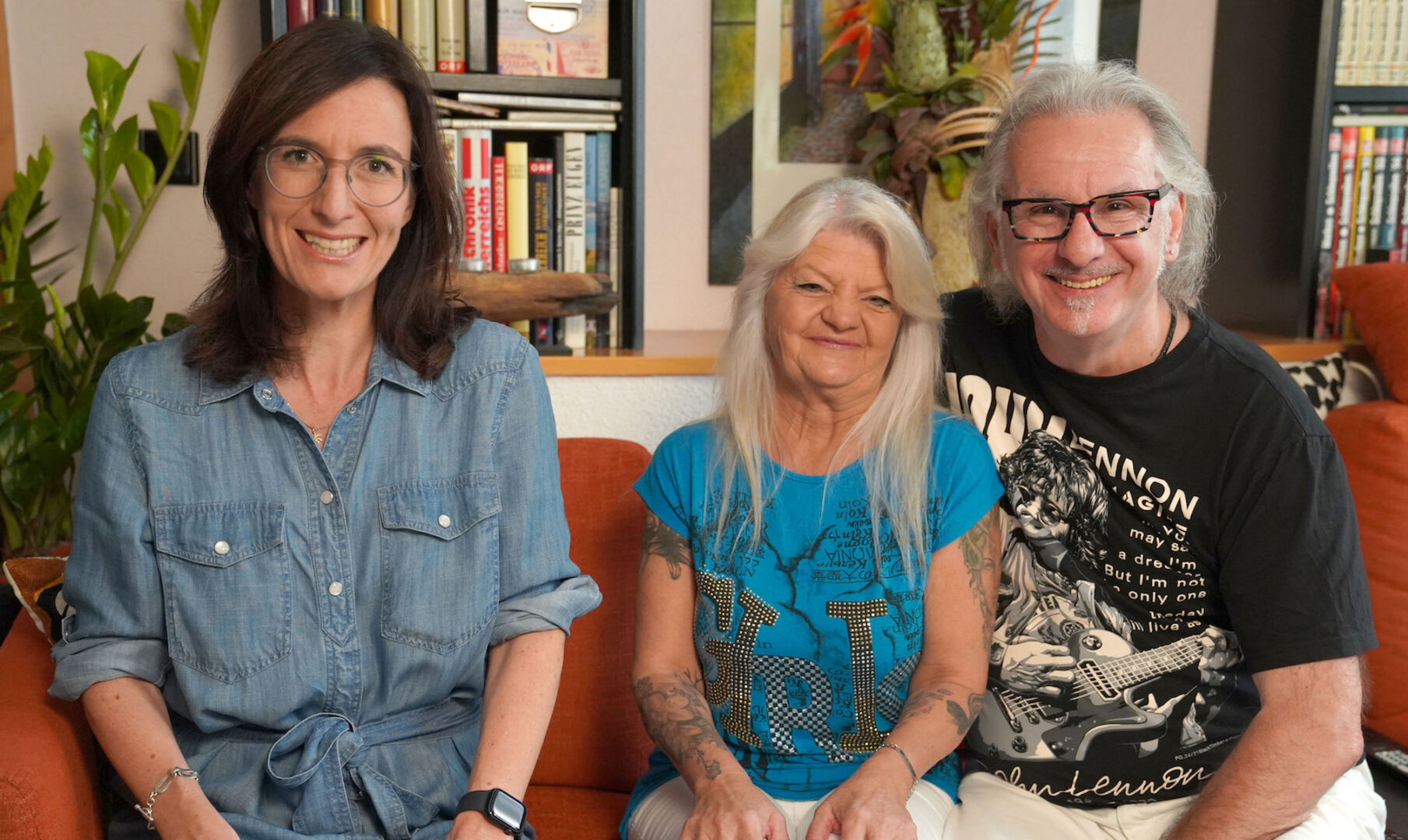 Nina Horowitz mit Silvia und Ernst, die ihre Liebe gefunden haben. Alle drei sitzen auf einem roten Sofa und tragen legere Kleidung.