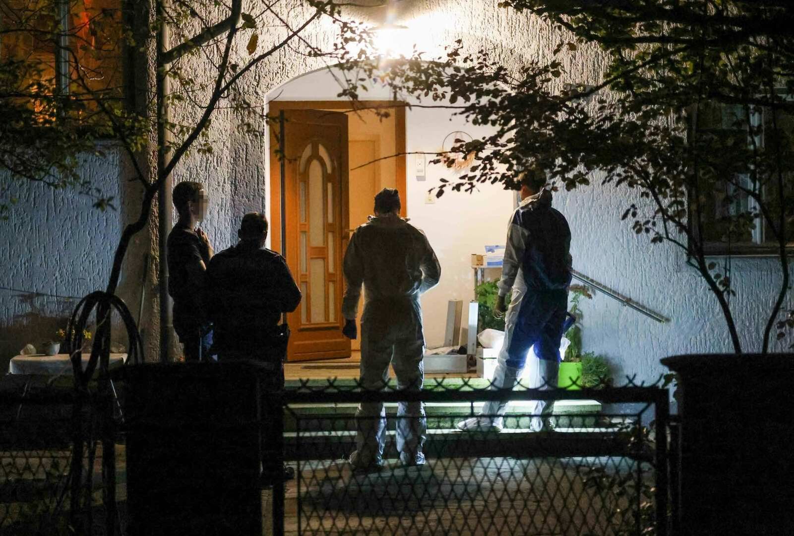 Vier Ermittler vor dem Haus, in dem die Tat geschehen ist.