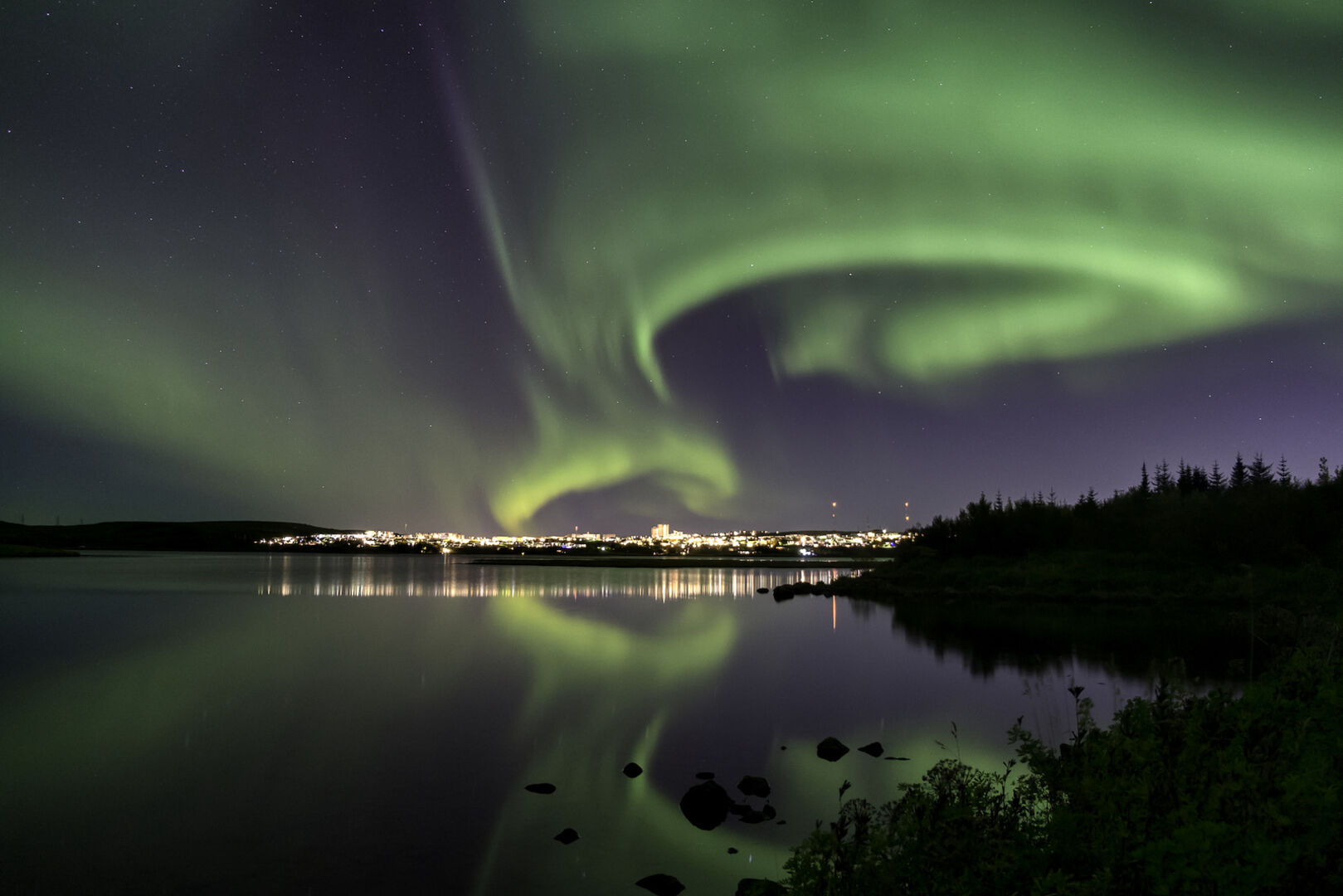 Reykjavik bei Nacht mit Polarlichtern am Himmel