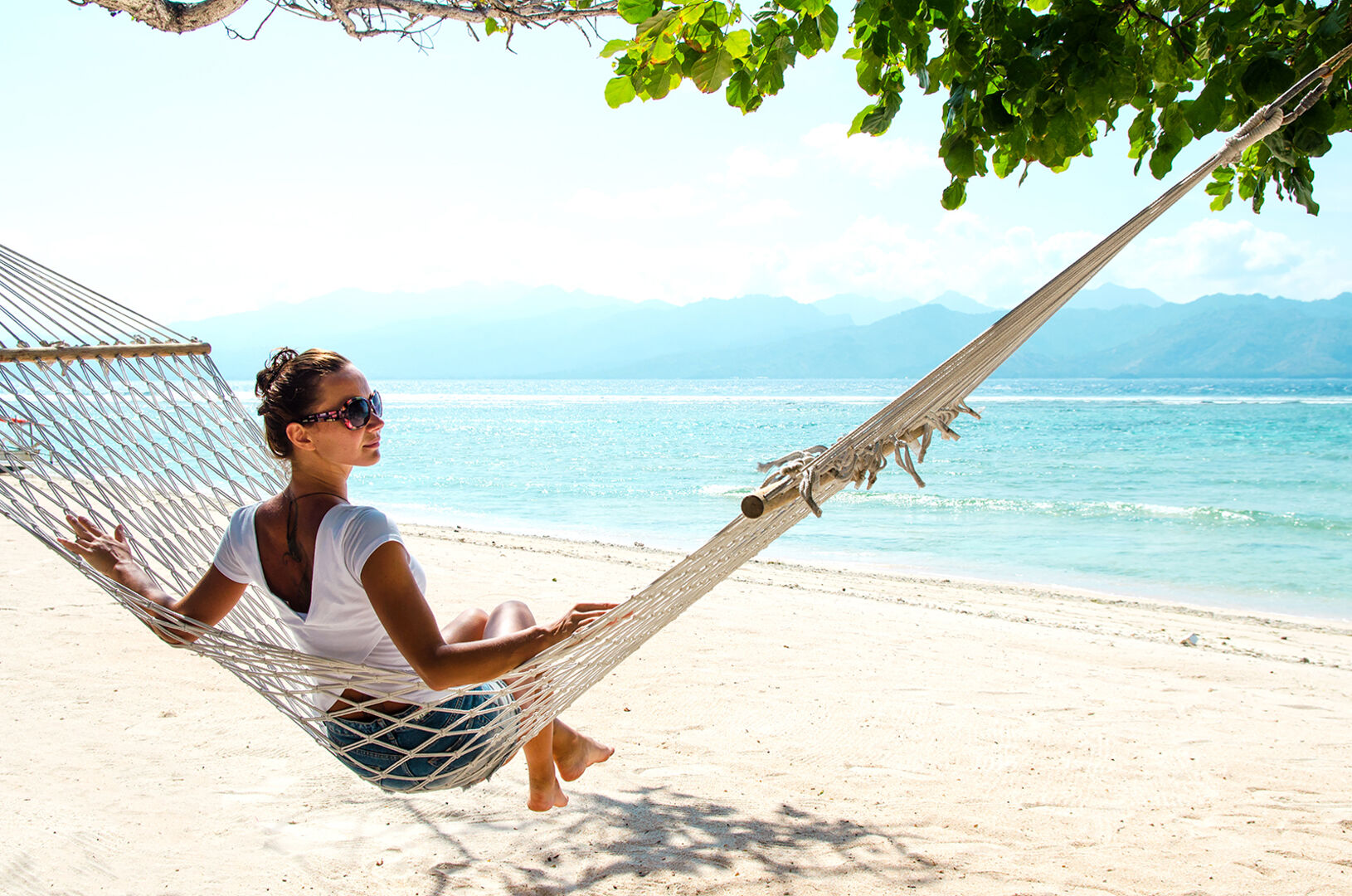 Frau sitzt am Strand | Credit: iStock.com/Hvoenok
