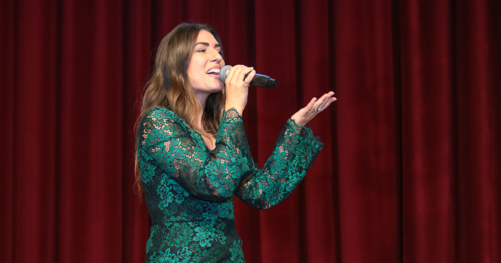 Sängerin mit Mikro in der Hand vor rotem Vorhang