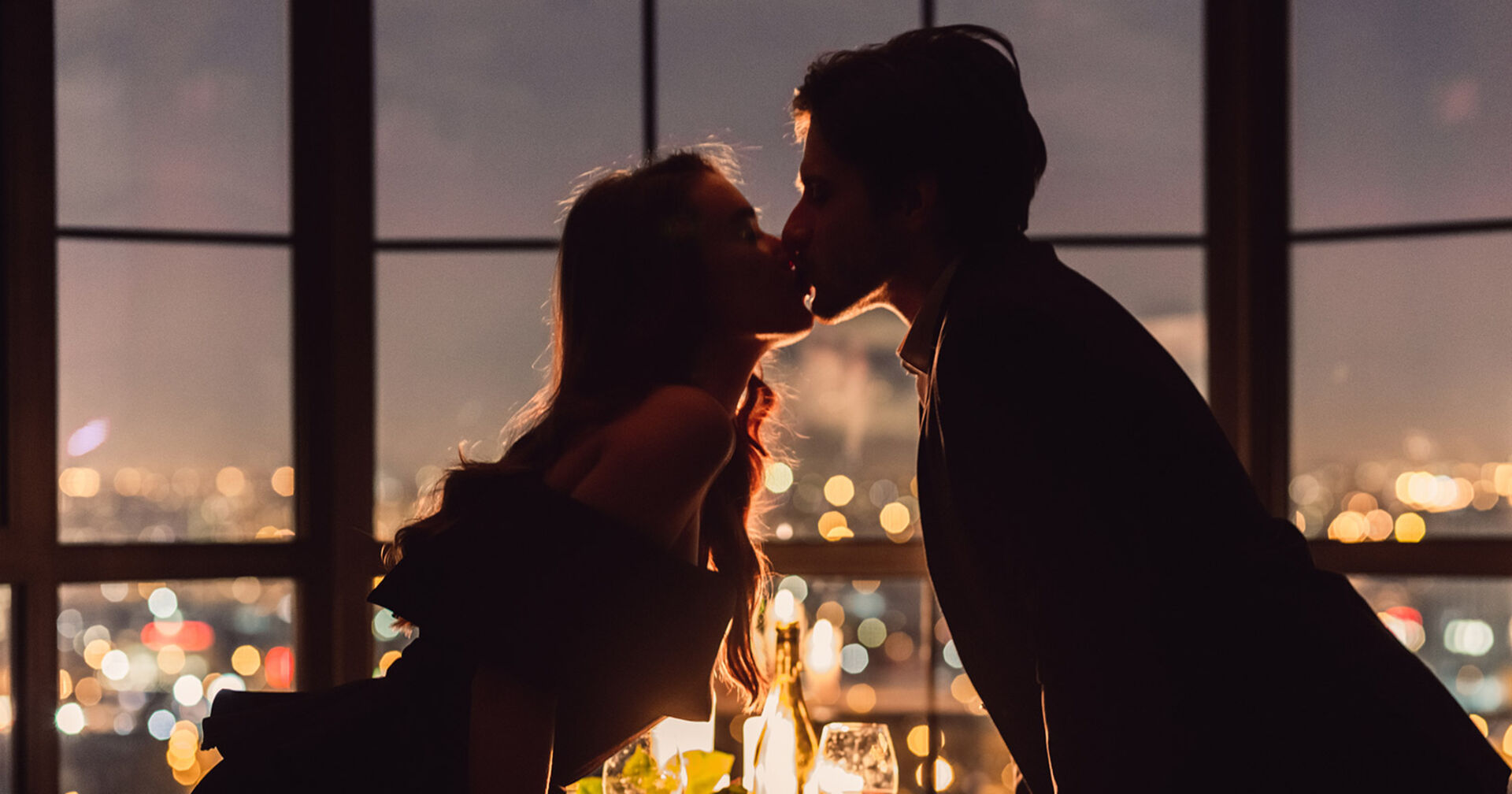 Paar küsst sich bei einem romantischen Dinner | Credit: iStock.com/Prostock-Studio