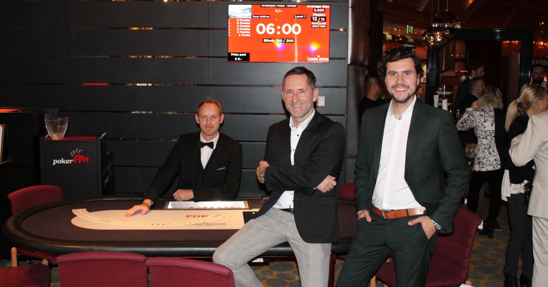 Daniel Klier und Thomas Wiegele stehen vor einem Pokertisch im Casino Velden, an dem ein Croupier sitzt