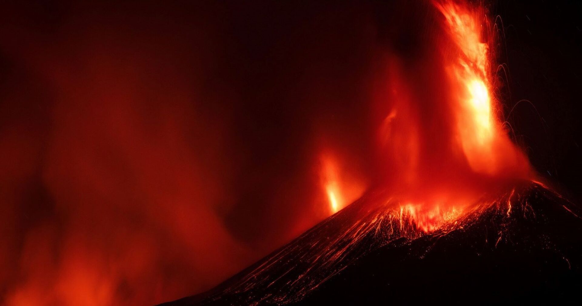 Ausbruch eines Vulkans bei Nacht, Lava schießt in die Höhe.