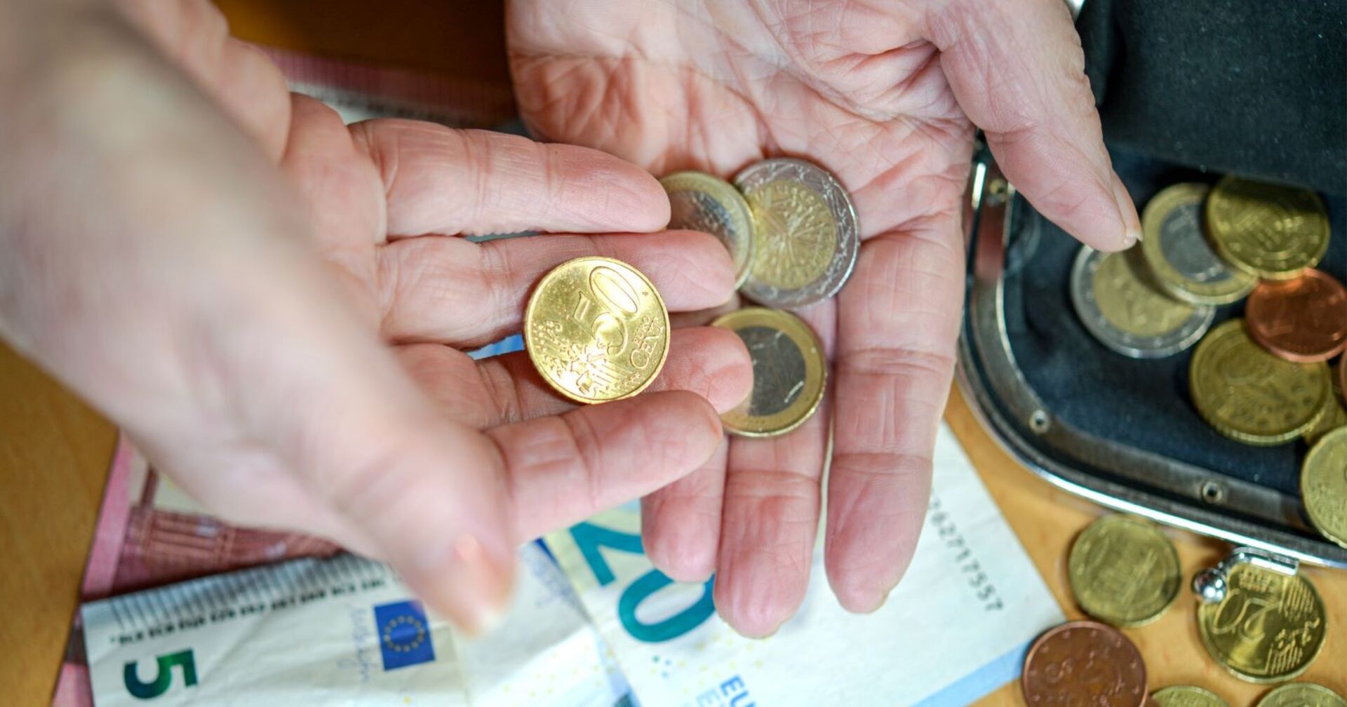 Hände in Nahaufnahme, der Inhalt ein Brieftasche wird gezählt, hauptsächlich Münzen
